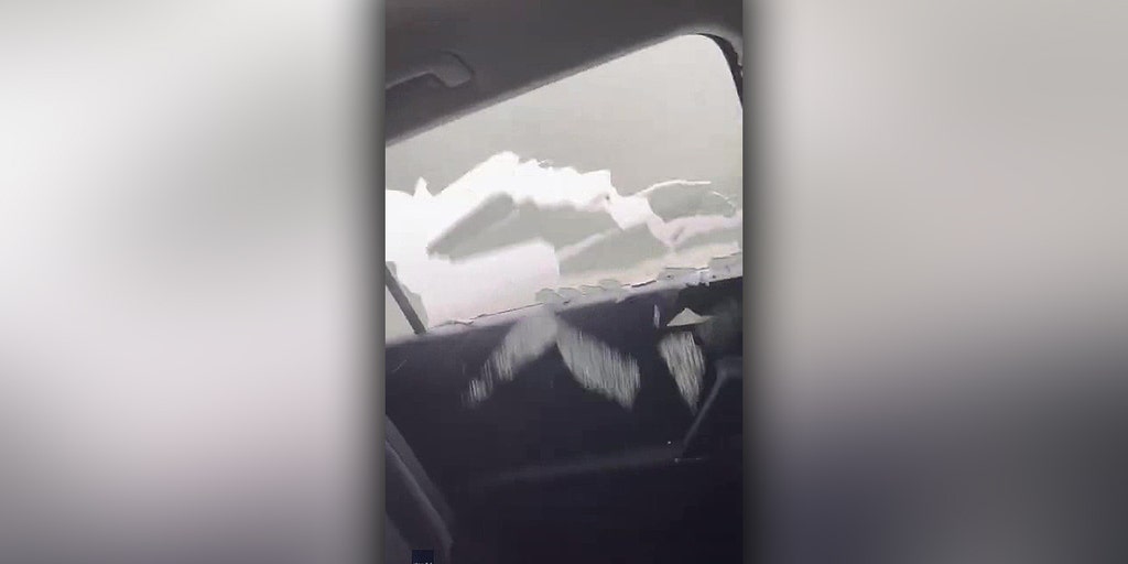 Watch as a record grapefruit-sized hailstorm pummels a car as three people shelter inside.